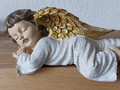 Schlafender Engel mit gold- und silberfarbigen Flügeln
